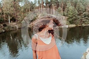 Smiling curly dark-haired woman feeling free and relived spending day in nature