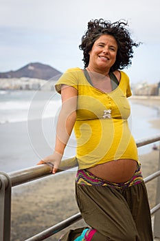 Smiling curly hair woman holding to beach walk railing