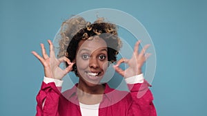 Smiling curly woman showing ok sign and looking at the camera