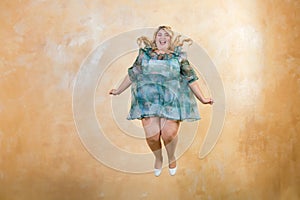 Smiling curvy female model in stylish outfit jumping