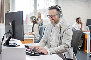 Smiling customer service executive with headset working in call center