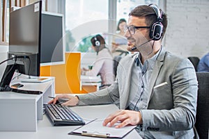 Smiling customer service executive with headset working in call center