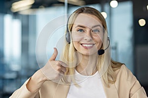 Smiling customer service representative with thumbs up, wearing a headset in a modern office setting