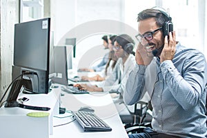 Smiling customer support operator with headphones and microphone working in call center