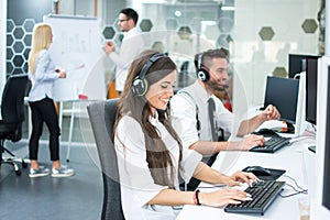 Smiling customer support operators working on computers at office.