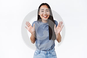 Smiling cute asian girl feeling awkward to refuse friend, raising hands up in surrender or rejection, grinning as saying