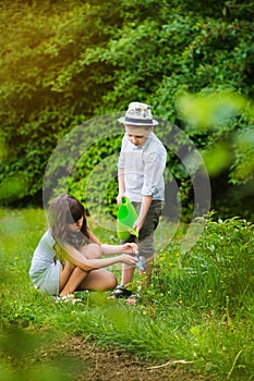 Smiling cute girl and blond boy cleaning horticultura tools in garden on sunny day. Happy childhood. Summer activities photo