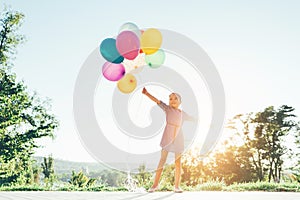 Smiling cute girl holding colorful balloons in the city park