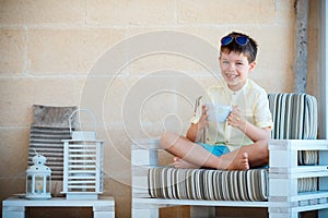 Smiling cute little boy drinking mug coffee tea hot drink