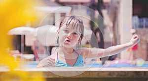 Smiling cute little child girl in pool in sunny day