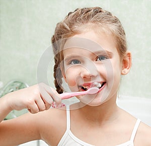 Smiling cute little girl brushing teeth