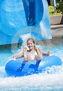 Smiling Cute little girl riding down a water slide at a water park