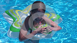 Smiling cute little girl with swim ring in swimming pool on sunny day
