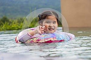 Smiling cute little girl in swimming pool in sunny day