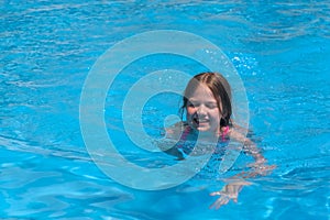 Smiling cute little girl in swimming pool on sunny summer day. Children beach fun