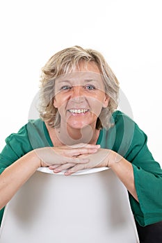 Smiling cute mature woman senior blond sitting on white background