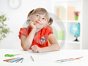 Smiling cute schoolgirl dreaming making homework