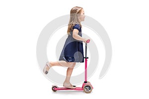 Smiling cute toddler girl three years riding a scooter over white background