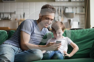 Smiling dad with kid son watching funny video on phone