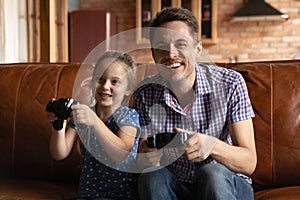Smiling dad and small daughter play video games