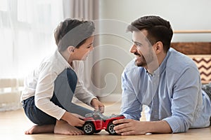 Smiling dad and son playing racing cars at home floor