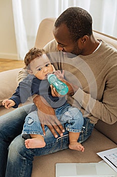 Smiling daddy feeding his little son