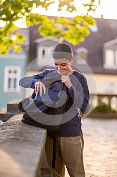 Smiling dark-haired adolescent rummaging in his schoolbag