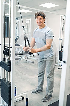 Smiling dark-haired man standing near training device