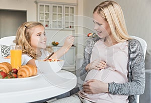 smiling daughter feeding pregnant