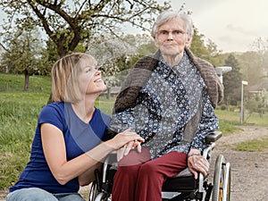Smiling daughter and grandmother with wheelchair