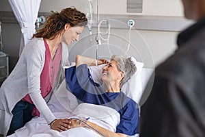 Smiling daughter and son visiting mother in hospital