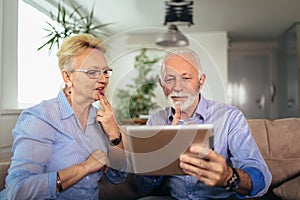 Smiling deaf senior couple talking using sign language on the digital tablet`s cam