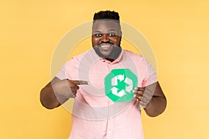 Smiling delighted man holding pointing at green recycling sign, saving environment.