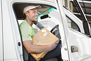 Smiling delivery driver in his van holding parcel