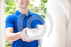 Smiling delivery man in blue uniform delivering parcel box to recipient