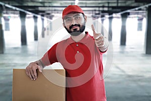 Smiling delivery man hold cardboard box