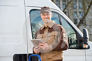 Smiling Delivery Man Holding Digital Tablet Against Truck