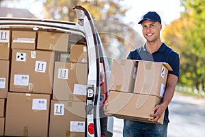Smiling delivery man loading boxes into his truck