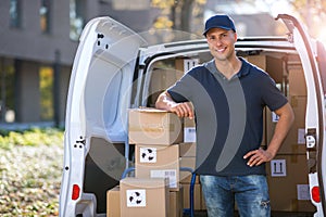 Smiling delivery man loading boxes into his truck