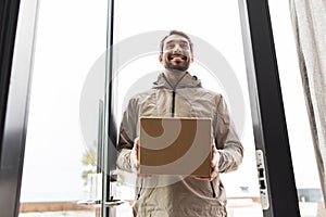 smiling delivery man with parcel box at open door