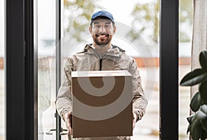 smiling delivery man with parcel box at open door