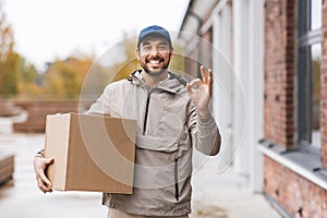 smiling delivery man with parcel box showing ok