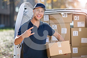 Smiling delivery man standing in front of his van holding a package