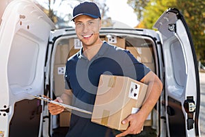 Smiling delivery man loading boxes into his truck