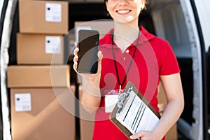 Smiling delivery worker in a uniform holding a smartphone