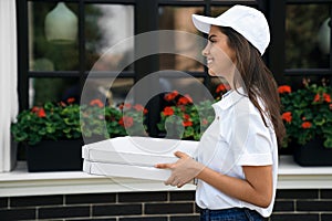 Smiling deliverywoman delivering boxes of pizza.