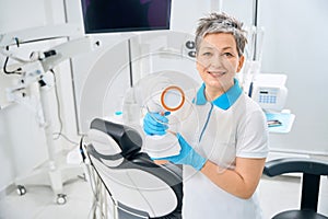 Smiling dental assistant holding portable dental x-ray device