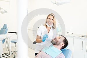 Smiling Dentist Examining Man in Dental Clinic