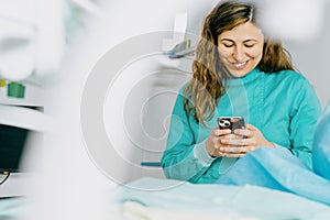 Smiling dentist in the operating room uses mobile phone