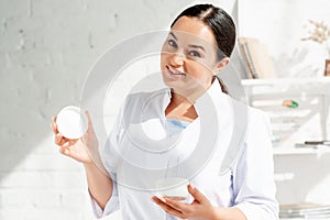 Smiling dermatologist holding cosmetic cream